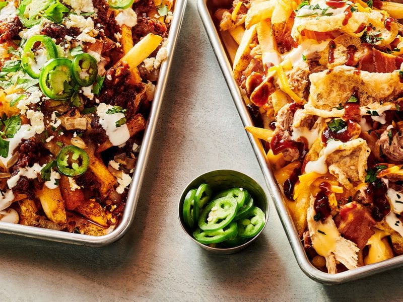 Two kinds of loaded french fries: one with alternative meat-free protein and one with two kinds of pork.