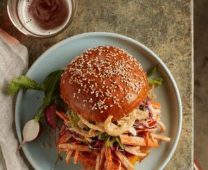 From-above photo of an imitation crab BBQ sandwich with coleslaw, with a small dish of BBQ sauce next to it.