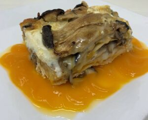 Plate of mushroom lasagna over a butternut squash puree on a white plate.