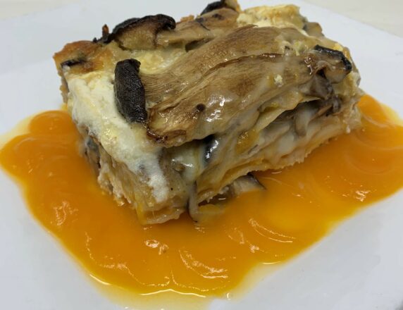 Plate of mushroom lasagna over a butternut squash puree on a white plate.